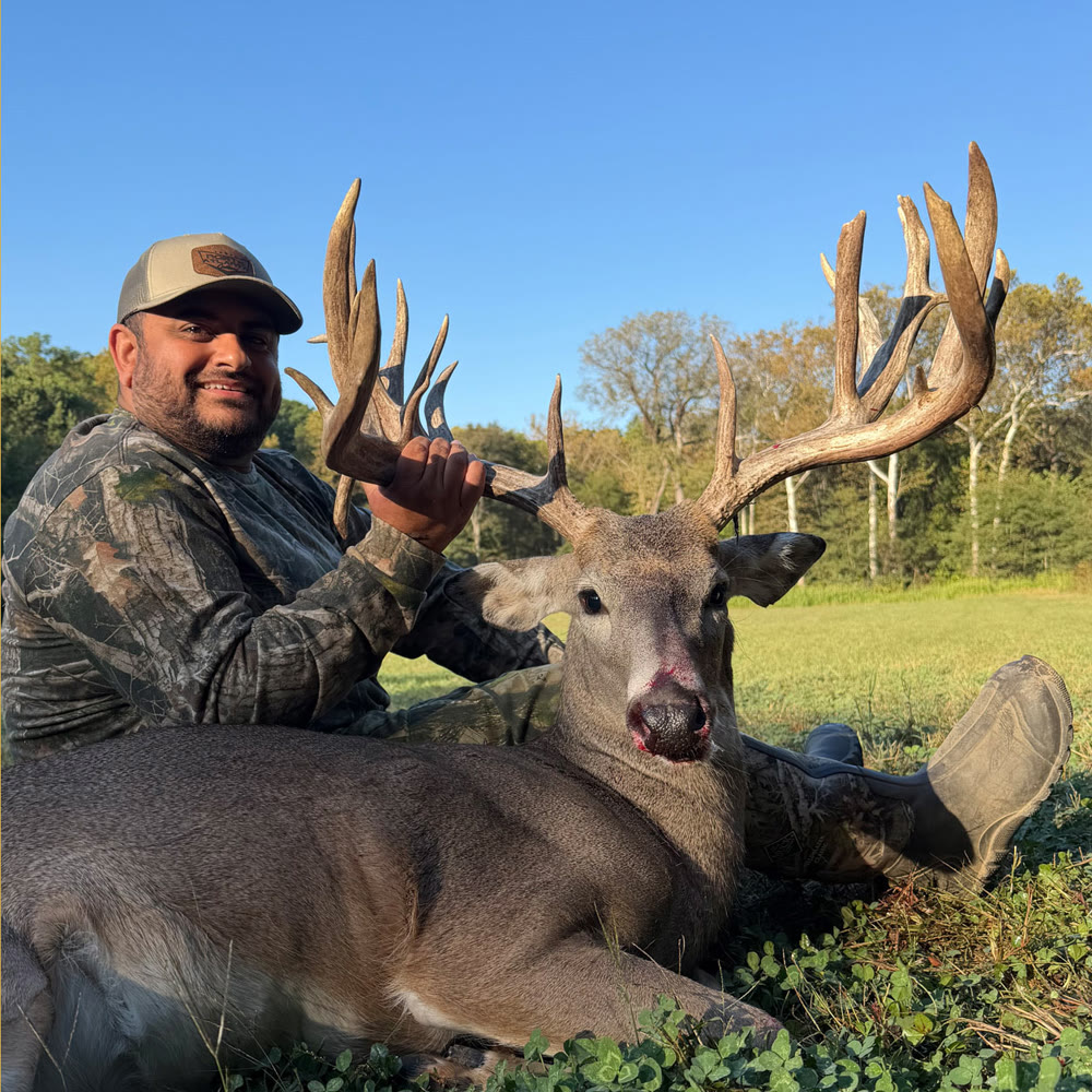 Hunter with a Gold-class whitetail buck harvested at Genesis Whitetails