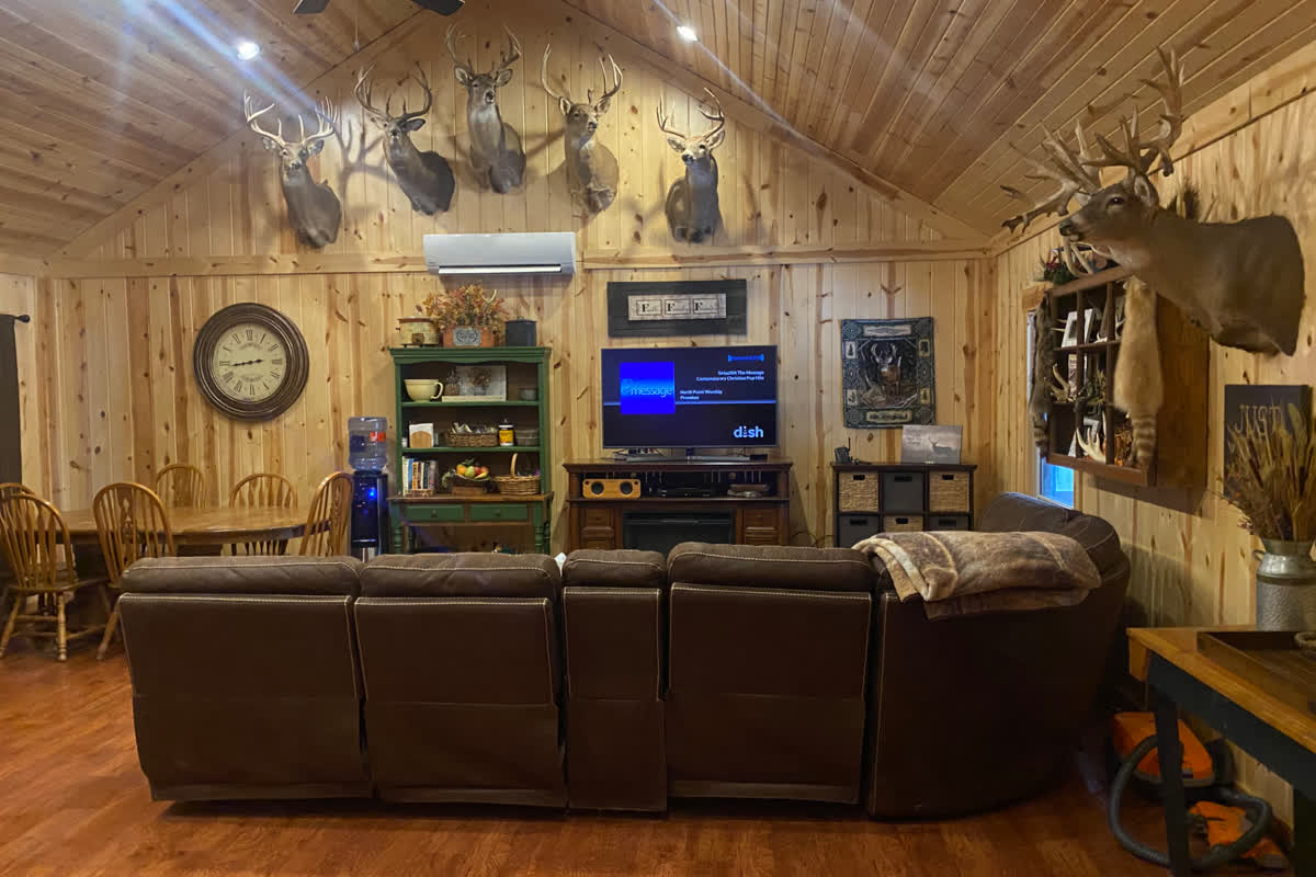 Lodge great room with leather sectional, fireplace, and mounted whitetail trophies