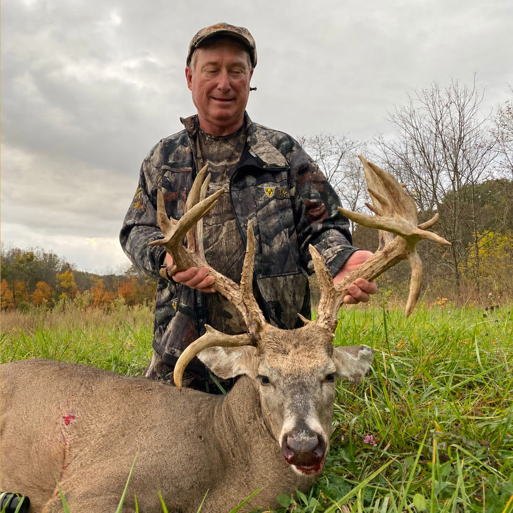 Hunter with a Bronze-class whitetail buck harvested at Genesis Whitetails