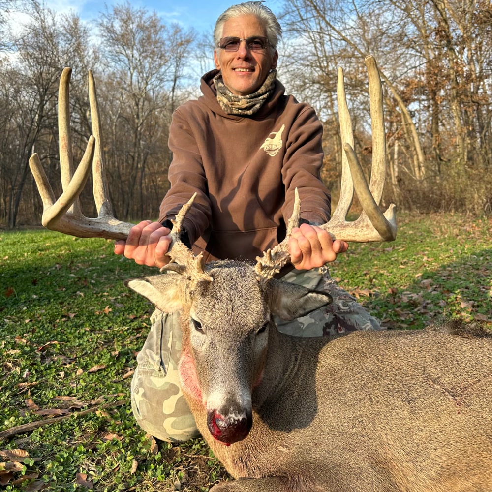 Hunter with a Silver-class whitetail buck harvested at Genesis Whitetails